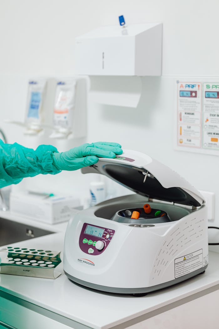 Lab professional operating a centrifuge in a clinical setting.